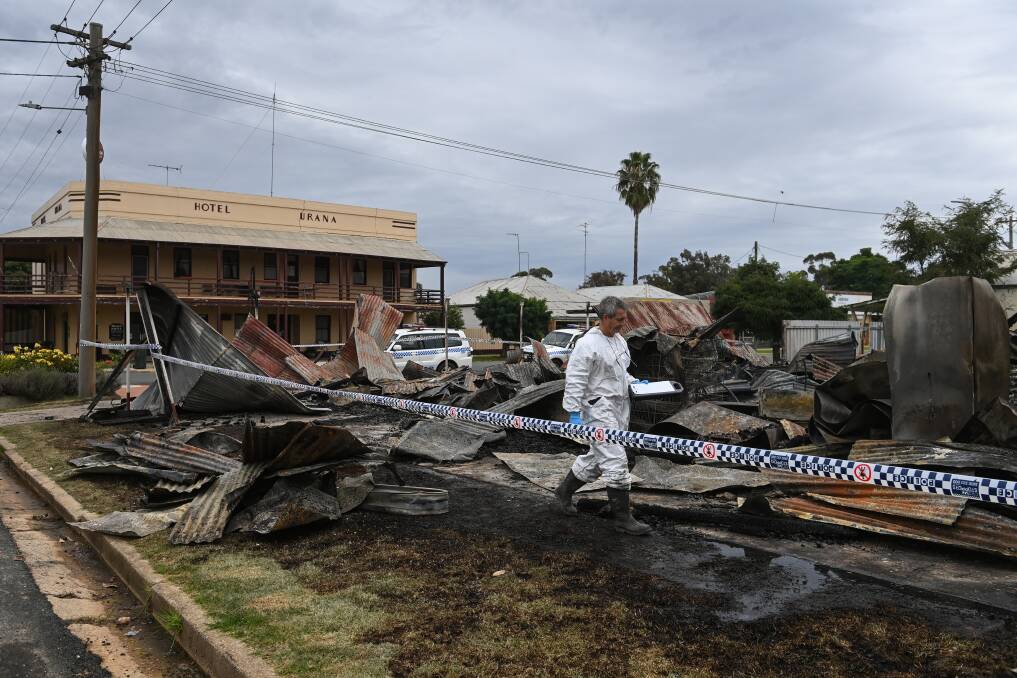 INVESTIGATION: A fire investigator searches through the flattened Urana business yesterday. Nearby resident Julie Barker thought the fire started in an area with chemicals and garden supplies. PHOTO: Mark Jesser